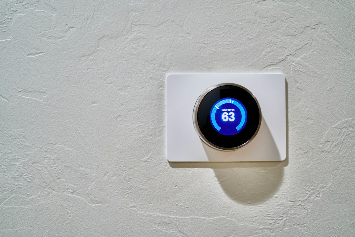 Smart thermostat on a wall, heat set to 63